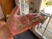 a person holding a green and gold necklace