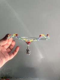 a person holding up a rainbow bead necklace