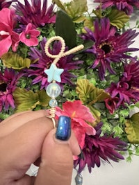 a person is holding a string of beads in front of flowers