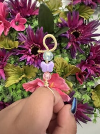 a person is holding a flower with a bead on it