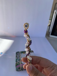 a person holding a purple beaded bracelet