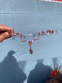 a person is holding up a necklace with a flower on it