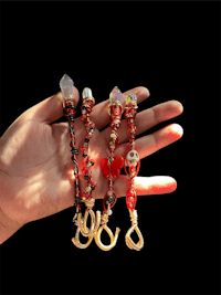 a person holding a pair of red and gold charms