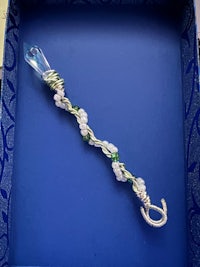 a blue box with a silver and green necklace in it