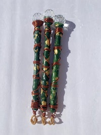 three green and gold beads on a white surface