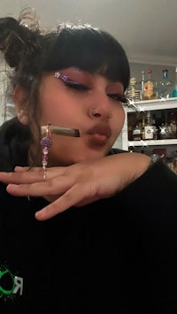 a girl is holding a cigarette in her hand