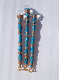 three blue and gold wands on a white surface