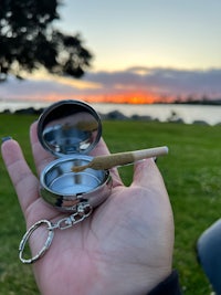a person holding a small glass container with a cigarette in it