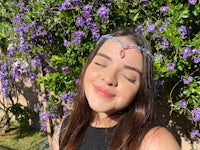 a woman wearing a blue headband in front of purple flowers