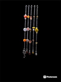 a necklace with beads and charms on a black background