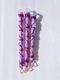 three purple and gold wands on a white surface