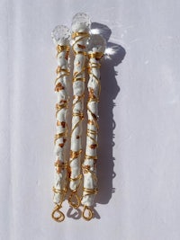 three white and gold tassels on a white surface