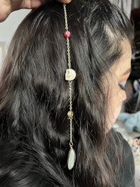 a woman's hair is being braided with a gold chain