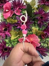 a person is holding a pink button in front of flowers