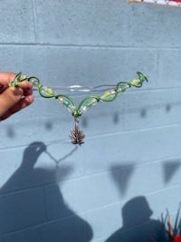 a person is holding up a necklace with green leaves