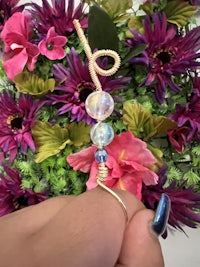 a person is holding a string of beads in front of flowers