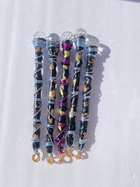 a group of black, purple, and gold necklaces on a white surface