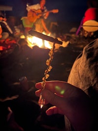 a person holding a cigarette in front of a campfire