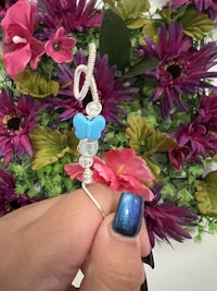 a person holding a blue glass bead with a flower on it